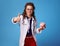 Happy physician woman with piggy bank showing thumbs up on blue