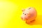 Happy piggy bank on yellow background, space for text