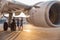 Happy pilot and two pretty stewardesses standing together, leaning on an airplane and smiling at camera after landing or