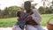 Happy playful Afro mother and son having fun in park doing a picnic together