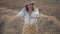 Happy playful woman falls into haystack in wheat field at sunset. Girl in straw hat and embroidered blouse smiling