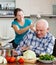 Happy playing mature couple cooking food