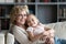 Happy pleasant senior retired grandmother relaxing on sofa with kid.