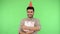 Happy pleased brunette man with party cone on head and in shirt embracing gift box. green background, chroma key