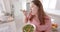 Happy plus size biracial woman eating vegetable salad standing in kitchen, slow motion