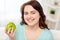 Happy plus size woman eating green apple at home