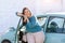 Happy plus size woman posing outside of the blue rental car in sunny day