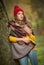 Happy Portrait fashion of a beautiful young Caucasian woman with a red cap and scarf and yellow pullover in autumn park,red green