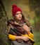 Happy Portrait fashion of a beautiful young Caucasian woman with a red cap and scarf and yellow pullover in autumn park,red green