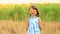 Happy portrait of little girl on field hides eye with sunflower