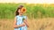 Happy portrait of little girl on field hides eye with sunflower