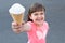 Happy portrait of the little girl with ice cream in a hand. White creamy ice cream