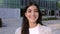 Happy portrait of young businesswoman standing over company office building