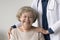 Happy positive elderly patient woman posing near geriatrician doctor