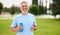 Happy positive mature man with broad smile holding water bottle while doing sport in city park