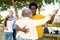 Happy positive mature multinational pensioners spending time together and dancing in pairs outdoors