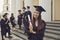 Happy positive pretty girl university graduate standing holding diploma in hand