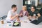 Happy and positive sutdents sit at table and talk. They work in bright room. Young woman hold tablet. Guy on right have