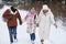 Happy pre-teen girl in winterwear holding by hands of her father and mother