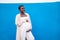 Happy pregnant african woman holding her belly in hands, smiling, posing on the blue wall outdoor. Real people lifestyle and
