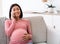 Happy Pregnant Asian Woman Talking On Phone Sitting At Home