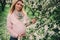 Happy pregnant blonde beautiful woman walking outdoor in spring park or garden