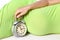 Happy pregnant girl with a clock an alarm clock for a child lies on a white background. Medicine for women with a child in the