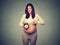 Happy pregnant woman with alarm clock expecting baby. Pregnancy concept