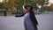 Happy pregnant woman in a black coat and big hat spins and smiles
