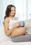 Happy pregnant woman with cup drinking tea at home