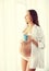 Happy pregnant woman with cup drinking tea at home