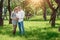 Happy pregnant woman, family couple in the park, green floral background. In anticipation of a miracle, a child. Family life,