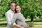Happy pregnant woman, family couple in the park, green floral background. In anticipation of a miracle, a child. Family life,