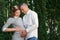 Happy pregnant woman, family couple in the park, green floral background. The child is jostling in the stomach. Family life,