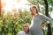 Happy pregnant woman, family couple in the park, green floral background. man listens to the belly of a beautiful pregnant wife.