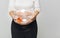 Happy pregnant woman holding a fishbowl with a goldfish in her h