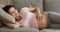 Happy pregnant woman lying on sofa strokes her big belly