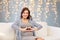 Happy pregnant woman making heart gesture at home