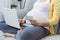 Happy pregnant woman pays order with credit card in online store at home. Online shopping