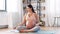 Happy pregnant woman with phone doing yoga at home