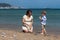 Happy pregnant woman playing with child boy on the beach