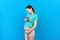 Happy pregnant woman showing small boots for a baby boy at Colored background. Future mother is waiting for a child