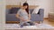 Happy Pregnant Woman sit on carpet holding stroking her big belly with diaper,feeding bottle,baby shoes at home.Pregnancy of young