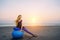 Happy pregnant woman sits on the exercise ball against sunset over the sea. Pregnancy, sport, fitness and healthy lifestyle