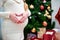 Happy pregnant woman sitting on floor and touching her belly over christmas tree background