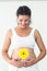 Happy pregnant woman touching her stomach while holding yellow flower