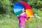 Happy pregnant woman walking under a colorful umbrella