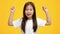 Happy Preschool Japanese Girl Shaking Fists Celebrating Success, Yellow Background