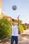 Happy preschooler boy in white t-shirt playing ball outdoors. Shirt mockup