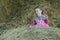 Happy preschooler girl wearing striped and plaid playing in country farm hayloft among dried loose grass hay
